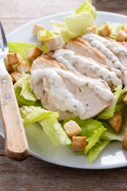 Tahta masada tavuklu çıtır Sezar salatası. Kapat.