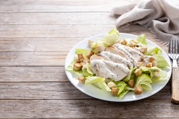 Tahta masada tavuklu çıtır Sezar salatası. Boşluğu kopyala