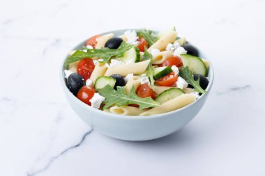 Akdeniz Makarna Salatası kasede Taze sebzeler ve beyaz mermer arka planda bitkiler