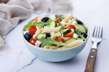 Akdeniz Makarna Salatası kasede Taze sebzeler ve beyaz mermer arka planda bitkiler