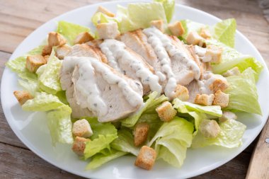 Tahta masada tavuklu gevrek Sezar salatası.