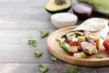 Lezzetli ızgara tavuk dürümü, sebzeli ve ahşap masada avokado. Boşluğu kopyala