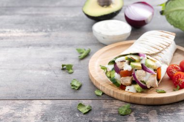 Lezzetli ızgara tavuk dürümü, sebzeli ve ahşap masada avokado. Boşluğu kopyala