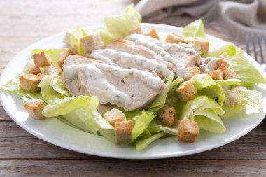 Tahta masada tavuklu gevrek Sezar salatası.