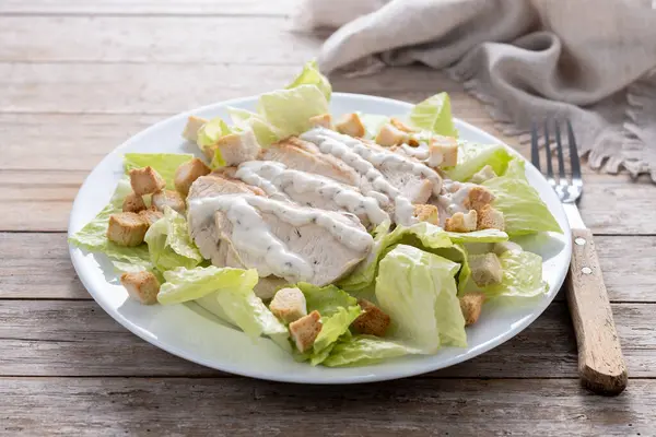 Tahta masada tavuklu gevrek Sezar salatası.