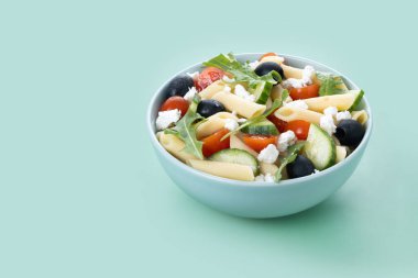 Akdeniz makarna salatası kasede taze sebzeler ve yeşil arka planda bitkiler. Boşluğu kopyala