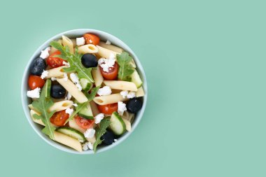 Akdeniz makarna salatası kasede taze sebzeler ve yeşil arka planda bitkiler. Üst Manzara. Boşluğu kopyala