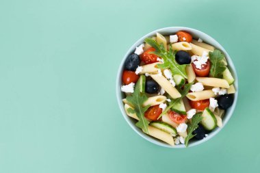 Akdeniz makarna salatası kasede taze sebzeler ve yeşil arka planda bitkiler. Üst Manzara. Boşluğu kopyala