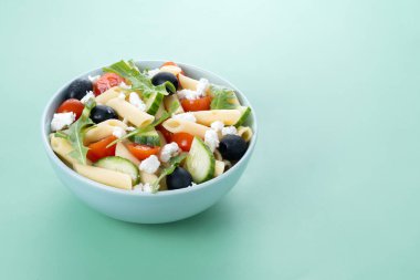 Akdeniz makarna salatası kasede taze sebzeler ve yeşil arka planda bitkiler. Boşluğu kopyala