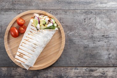 Lezzetli ızgara tavuk dürümü, sebzeli ve ahşap masada avokado. Üst Manzara. Boşluğu kopyala