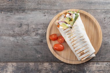 Lezzetli ızgara tavuk dürümü, sebzeli ve ahşap masada avokado. Üst Manzara. Boşluğu kopyala