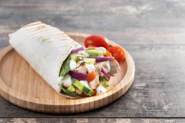 Lezzetli ızgara tavuk dürümü, sebzeli ve ahşap masada avokado. Boşluğu kopyala