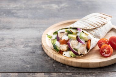 Lezzetli ızgara tavuk dürümü, sebzeli ve ahşap masada avokado. Boşluğu kopyala