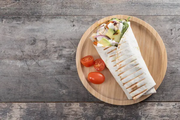 Lezzetli ızgara tavuk dürümü, sebzeli ve ahşap masada avokado. Üst Manzara. Boşluğu kopyala