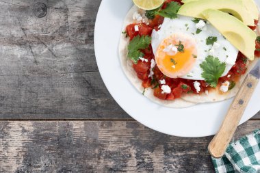 Huevos Rancheros. Geleneksel Meksika kahvaltısı ahşap masada. Üst Manzara. Boşluğu kopyala