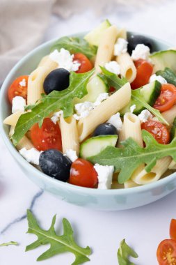 Akdeniz Makarna Salatası kasede Taze sebzeler ve beyaz mermer arka planda bitkiler