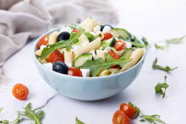 Akdeniz Makarna Salatası kasede Taze sebzeler ve beyaz mermer arka planda bitkiler