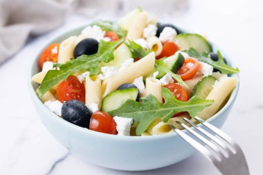 Akdeniz Makarna Salatası kasede Taze sebzeler ve beyaz mermer arka planda bitkiler