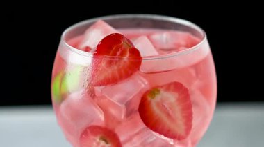 Siyah arkaplanda çilekli cin tonik kokteyli dönüyor