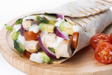 Beyaz arka planda, sebzeli ve avokadolu nefis bir ızgara tavuk dürümü.