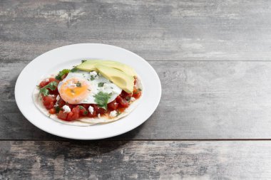 Huevos Rancheros ahşap masada. Uzayı kopyala Geleneksel Meksika kahvaltısı.