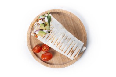 Beyaz arka planda, sebzeli ve avokadolu nefis bir ızgara tavuk dürümü.