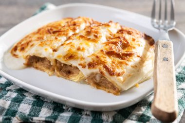 Peynirli ve ahşap masada Bechamel soslu fırında etli cannelloni.