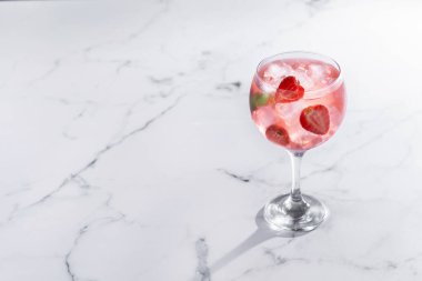 Beyaz mermer arka planda çilekli cin tonik kokteyli.