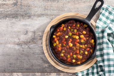 Tahta masada demir tavada sebzeli Meksika fasulyesi. Üst Manzara. Boşluğu kopyala