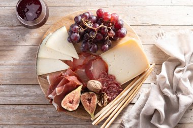 Peynirli, üzümlü, incirli ve ahşap masadaki şaraplı şarküteri tahtası.
