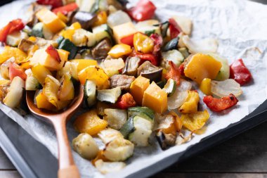 Kızarmış sebzeler, siyah arka planda fırın tepsisinde.