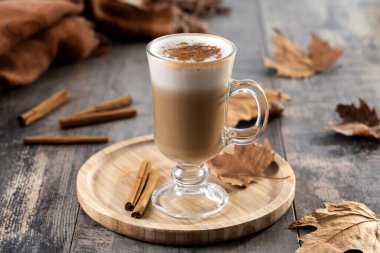 Ahşap masada, cam bardakta tarçınlı akçaağaç latte.