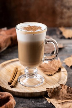 Ahşap masada, cam bardakta tarçınlı akçaağaç latte.