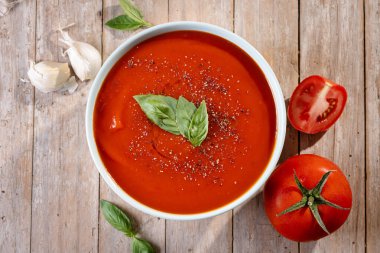 Tahta masada taze fesleğen yapraklarıyla süslenmiş ev yapımı kremalı domates çorbası.