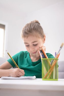 Evde ödevlerini yaparken, İç İşleri 'ndeki Not Defteri' nde yazan genç kız.