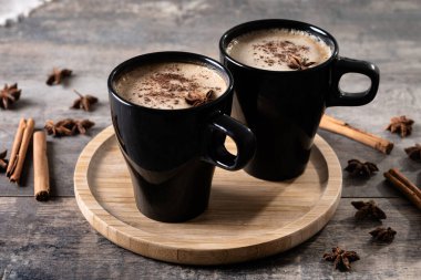 Kara bardakta Chai Latte ve Baharatlar (yıldız anason ve tarçın) ahşap masa üzerinde