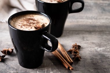 Kara bardakta Chai Latte ve Baharatlar (yıldız anason ve tarçın) ahşap masa üzerinde