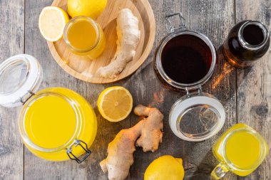 Ahşap masada ev yapımı kombu çayıyla dolu çeşitli cam kavanozlar ve şişeler.