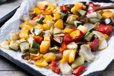 Ahşap masadaki fırın tepsisinde kızartılmış sebzeler.