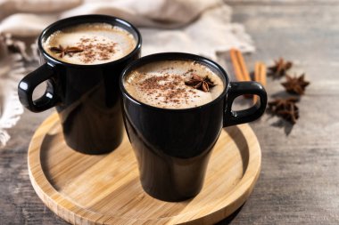 Kara bardakta Chai Latte ve Baharatlar (yıldız anason ve tarçın) ahşap masa üzerinde