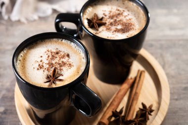 Kara bardakta Chai Latte ve Baharatlar (yıldız anason ve tarçın) ahşap masa üzerinde