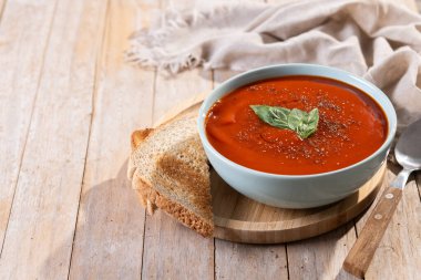 Ev yapımı domates çorbası ve ahşap masada fesleğen. Boşluğu kopyala