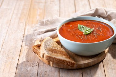 Ev yapımı domates çorbası ve ahşap masada fesleğen. Boşluğu kopyala