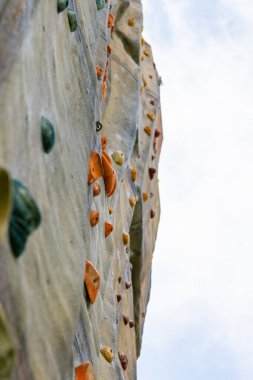 Renkli tırmanışların yakın çekim görüntüsü yapay bir kaya duvarını tutuyor..
