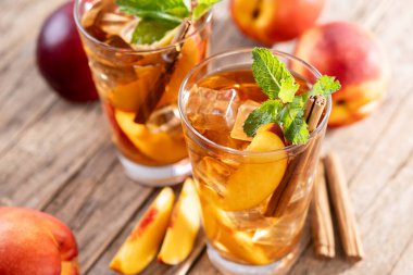 Şeftalili buzlu çayı bardakta, buz küpleriyle ahşap masada tazeliyorum.