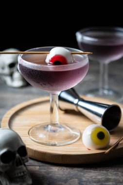 Ahşap masada şekerle süslenmiş mor Cadılar Bayramı kokteyli.