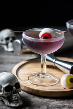 Ahşap masada şekerle süslenmiş mor Cadılar Bayramı kokteyli.