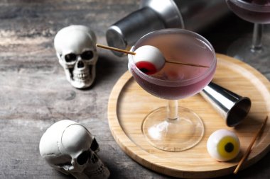 Ahşap masada şekerle süslenmiş mor Cadılar Bayramı kokteyli.