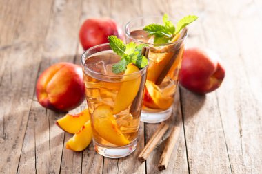 Şeftalili, buzlu çayı bardakta, buz küpleriyle ve ahşap masada tarçınla tazeliyorum.