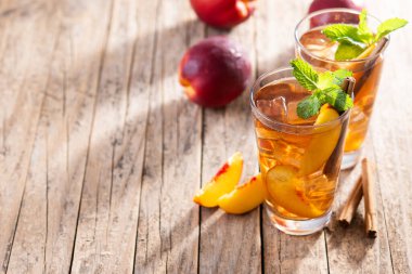 Şeftalili buzlu çayı, buz küpleri ve ahşap masada tarçın ile tazeliyorum. Boşluğu kopyala